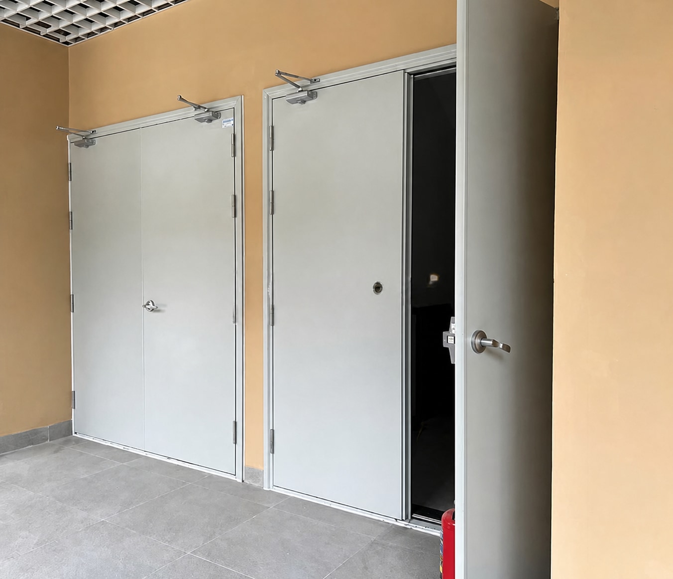 Ba bộ cửa chống cháy hai cánh đã lắp trong hành lang công trình, có tay co thuỷ lực tự đóng