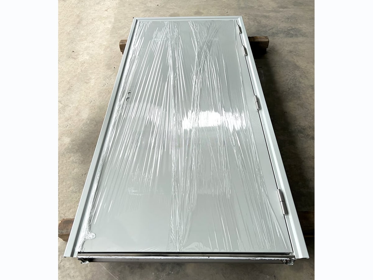 Bộ cửa chống cháy còn bọc màng, đặt trên kê gỗ tại công trình trước khi lắp
